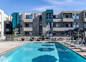 Thumbnail 30 of 54 - a pool with chairs and umbrellas in front of a building