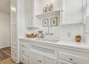 Thumbnail 2 of 40 - A white kitchen with a sink and a potted plant.