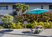 Thumbnail 26 of 37 - A blue umbrella is on a table in the middle of a courtyard.