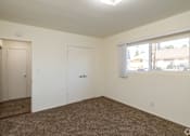 Thumbnail 22 of 37 - A room with carpeted floor, two doors, and a window.