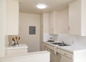 Thumbnail 25 of 37 - A small kitchen with white cabinets and a white counter top.