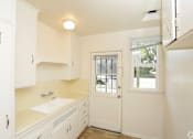Thumbnail 1 of 47 - A small kitchen with white cabinets and a white door.