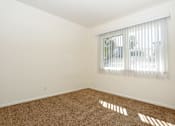 Thumbnail 4 of 47 - A room with a carpeted floor and a window with blinds.