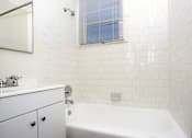 Thumbnail 7 of 47 - A white bathroom with a tub, sink, and mirror.