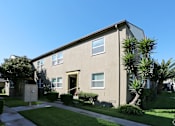Thumbnail 13 of 47 - A beige building with a brown door and windows.