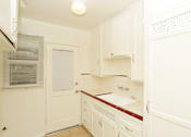 Thumbnail 23 of 47 - A white kitchen with a red counter.