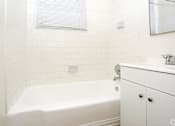Thumbnail 44 of 47 - A white bathroom with a tub, sink, and mirror.