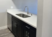 Thumbnail 19 of 54 - an empty kitchen with black cabinets and a stainless steel sink