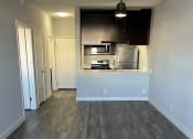 Thumbnail 21 of 54 - an empty living room with wood floors and a kitchen