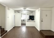 Thumbnail 26 of 31 - an empty living room with a ceiling fan and a kitchen