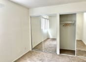 Thumbnail 29 of 31 - an empty bedroom with mirrored closet doors and carpeted flooring