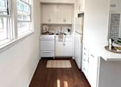 Thumbnail 12 of 30 - A kitchen with white cabinets and a fan on the ceiling.
