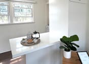 Thumbnail 16 of 30 - A white reception desk with a fan on the ceiling and a plant on the desk.