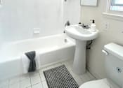 Thumbnail 21 of 30 - A white bathroom with a white toilet, sink, and tub.