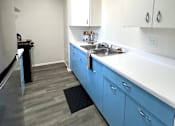 Thumbnail 5 of 30 - A kitchen with blue cabinets and a white counter.