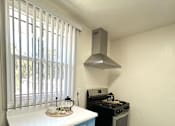 Thumbnail 4 of 30 - A kitchen with a stove and a window with blinds.