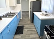 Thumbnail 3 of 30 - A kitchen with blue cabinets and a black refrigerator.