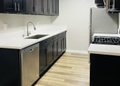 Thumbnail 14 of 40 - a kitchen with black cabinets and a sink and a refrigerator