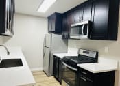 Thumbnail 15 of 40 - a kitchen with black cabinets and stainless steel appliances