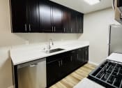 Thumbnail 17 of 40 - a kitchen with black cabinets and a white counter top and a stove and refrigerator