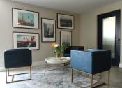 Thumbnail 11 of 31 - a living room with blue chairs and a table and pictures on the wall