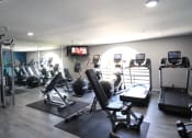 Thumbnail 14 of 31 - a gym with cardio equipment and a tv on the wall