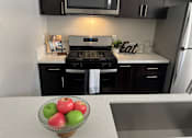 Thumbnail 41 of 45 - a kitchen with black cabinets and a bowl of apples