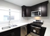 Thumbnail 1 of 20 - A kitchen with black cabinets and stainless steel appliances and a window