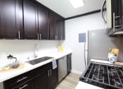 Thumbnail 2 of 31 - a kitchen with black cabinets and stainless steel appliances and a stove