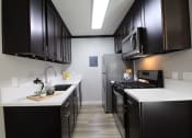 Thumbnail 1 of 31 - a kitchen with black cabinets and white counter tops and a stainless steel refrigerator