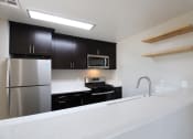Thumbnail 12 of 45 - a apartment kitchen with upgraded black cabinets and a white counter top