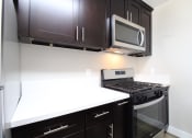 Thumbnail 29 of 45 - a kitchen with a stove and microwave and dark cabinets