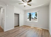 Thumbnail 37 of 40 - A room with a ceiling fan and a window showing a tree outside.