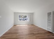 Thumbnail 33 of 40 - A room with wooden floors and a window showing a view of trees.