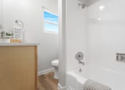 Thumbnail 12 of 40 - A white bathroom with a tub, toilet, and sink.
