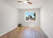 Thumbnail 30 of 40 - A room with a ceiling fan and a window with a view of the outside.