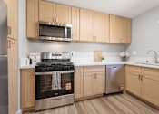 Thumbnail 6 of 40 - A kitchen with wooden cabinets and stainless steel appliances.