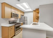 Thumbnail 18 of 30 - A kitchen with a white countertop and wooden cabinets.
