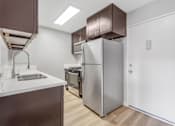 Thumbnail 7 of 35 - A modern kitchen with a stainless steel refrigerator and a white sink.