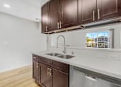 Thumbnail 9 of 35 - A kitchen with brown cabinets and a stainless steel dishwasher.