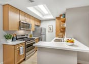 Thumbnail 2 of 30 - A modern kitchen with wooden cabinets and stainless steel appliances.