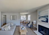 Thumbnail 57 of 59 - A living room with a grey couch and a fireplace.