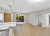 Thumbnail 22 of 30 - A spacious room with wooden floors and white walls.