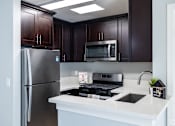 Thumbnail 27 of 37 - A kitchen with a refrigerator, microwave, and stove.