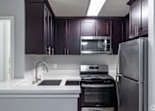 Thumbnail 9 of 37 - A modern kitchen with dark brown cabinets and stainless steel appliances.