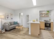 Thumbnail 5 of 49 - A modern kitchen and living room with a grey couch and wooden coffee table.