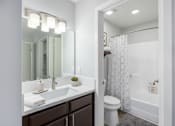 Thumbnail 5 of 34 - A white toilet sits in a bathroom next to a white sink.