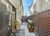 Thumbnail 22 of 34 - A patio with a table and chairs is surrounded by a brick wall.