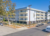 Thumbnail 31 of 45 - an image of an apartment building with cars parked in front of it