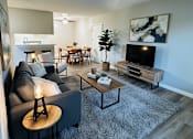 Thumbnail 1 of 36 - A living room with a grey couch, a wooden coffee table, and a television.